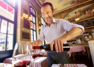 un homme sert du vin à table à ses amis