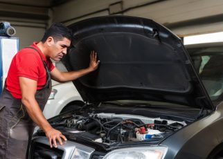 un garagiste regarde le moteur d'une voiture qui à le capot ouvert